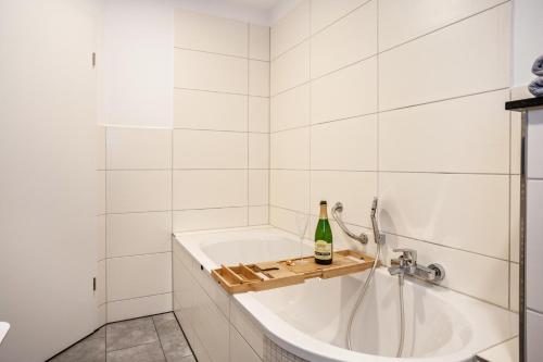 a white bathroom with a tub with a bottle of champagne at Salerhof in Bad Wurzach
