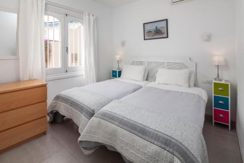 a white bedroom with a large bed and a window at Bright spacious 1 bed apartment in Nerja