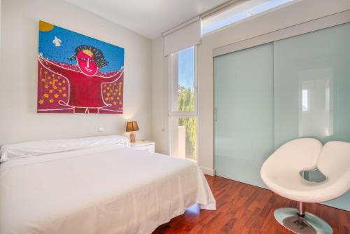 a bedroom with a white bed and a painting on the wall at Traviata in Cap Blanc