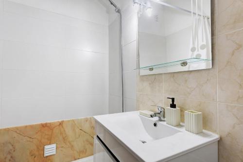 a white bathroom with a sink and a mirror at Oasis de Ferrel in Ferrel