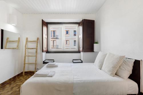 a bedroom with a large white bed with a window at Oasis de Ferrel in Ferrel
