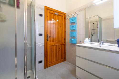 a bathroom with a sink and a wooden door at Casa con terrazza nella Pineta in Codaruina