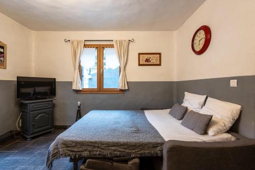 a bedroom with a bed and a clock on the wall at Joli Appartement Sur Le Bois in Aigueblanche