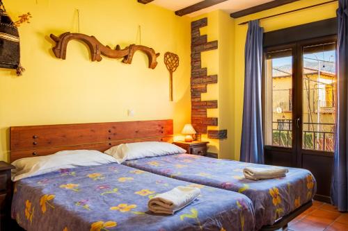 a bedroom with two beds and a window at Casa Rural El Barranco in Mombeltrán