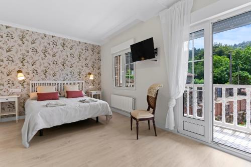 a bedroom with a bed and a tv and a window at La Casuca del Músico in Novales