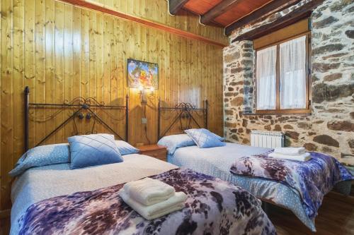 two beds in a room with wooden walls at Casa Rural Abuelo Jose in Robledo de las Traviesas
