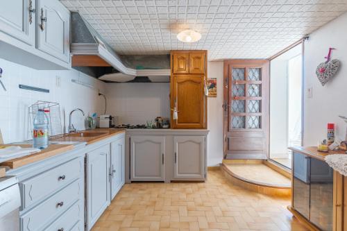 a kitchen with white cabinets and a wooden floor at Les Cerisiers in Apt