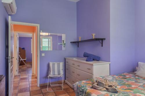 a bedroom with purple walls and a bed and a dresser at Bungalow El Caserío De Merengue in San Bartolomé