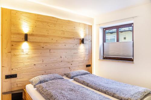 two beds in a bedroom with a wooden wall at Ammerstube Oberammergau in Oberammergau