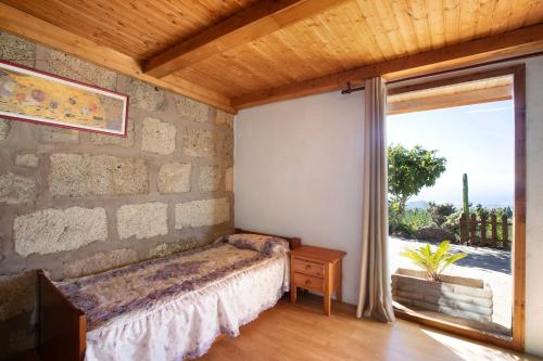 a bedroom with a stone wall with a bed and a window at El cazador 2 in Granadilla de Abona