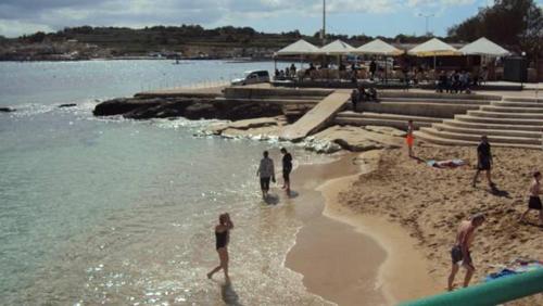 a group of people playing in the water on a beach at Marsascala Interlace Apartment with free parking in Marsaskala
