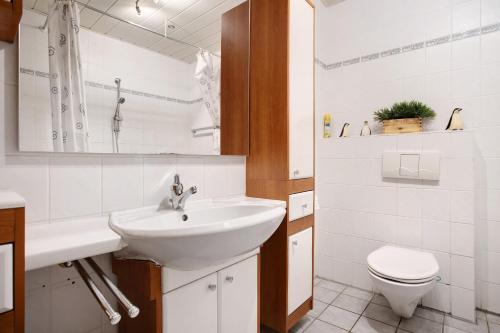 a white bathroom with a sink and a toilet at Ferienwohnung K Schröder in Sundhagen-Niederhof