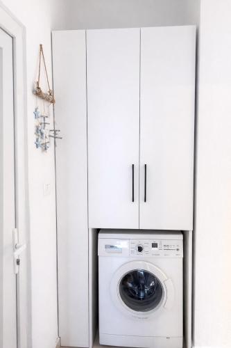a washing machine in a white laundry room with white cabinets at DoR Stay Seaside in Durrës