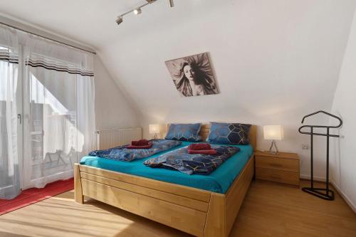 a bedroom with a bed with blue sheets and a window at Ferienwohnungen Hog , Ringsheim in Ringsheim