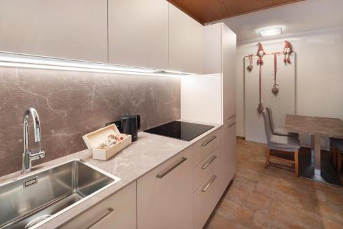 a kitchen with white cabinets and a sink and a table at Guesthouse Canazei Cozy 2-Bedrooms in Canazei