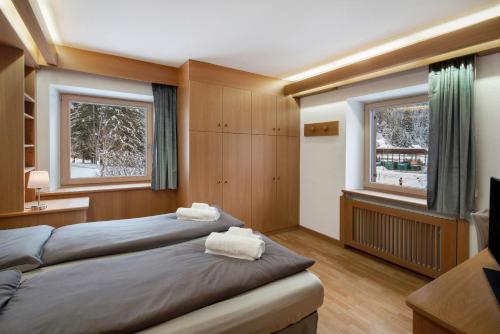a bedroom with two beds and two windows at Guesthouse Canazei Cozy 2-Bedrooms in Canazei