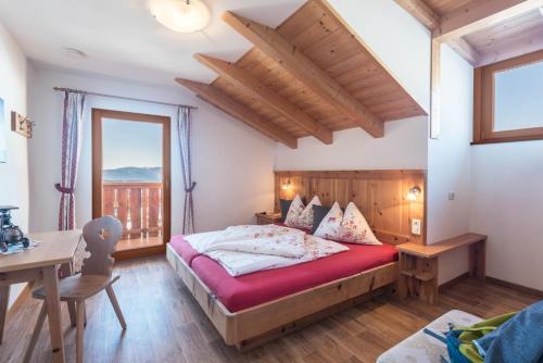 a bedroom with a bed and a desk and a window at Schildberghof Panorama in Kastelruth