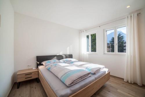 a bed with pillows on it in a room with a window at City Apartment Flora in Merano