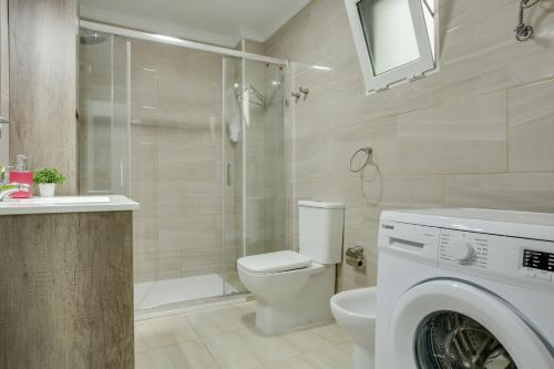 a bathroom with a shower toilet and a washing machine at 2b El Amore in Vecindario