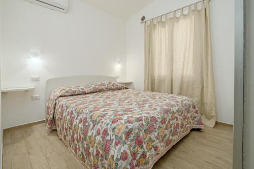 a bedroom with a bed with a colorful bedspread and a window at Confortevole villetta caposchiera in San Teodoro