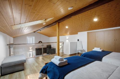 two beds in a room with wooden ceilings at Moradia Dos Castelos Azul in Ourém