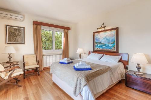 a bedroom with a bed and a chair and a window at Villa Almeda in Port d'Andratx