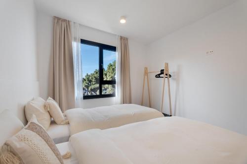 a bedroom with two white beds and a window at Buena - Vista in La Guancha