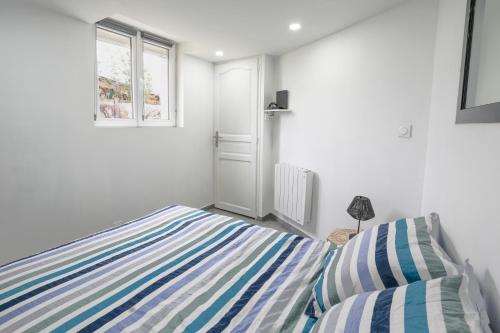 a bedroom with a striped bed and a window at Appartement dans maison atypique in Montrond-les-Bains