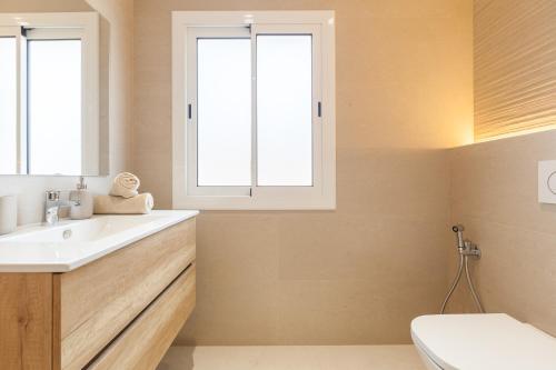 a bathroom with a sink and a toilet and two windows at Blue Coast Apartment in Canet de Mar