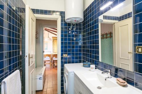 a blue tiled bathroom with a sink and a mirror at Casa Mucchi Bianchi PC33 in Arzachena
