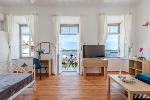 a bedroom with a bed and a tv and windows at Martha's House in Spetses