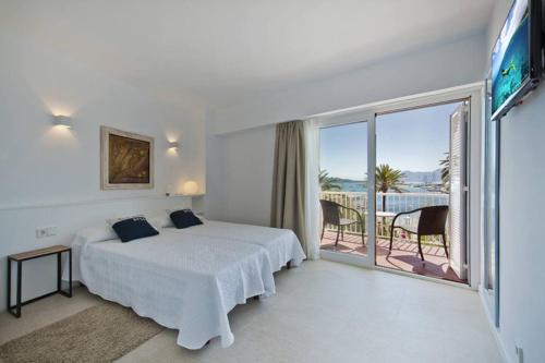 a white bedroom with a bed and a balcony at Maina 1919 in Pollença
