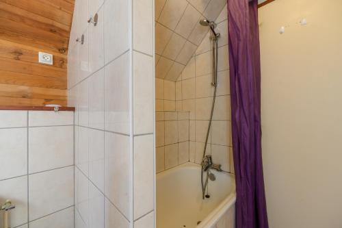 a bathroom with a tub and a shower with purple curtains at Chalet les moraines 8 in Le Tholy