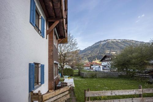 a house with blue windows and a fence and a mountain at Haus Bergliebe in Pfronten
