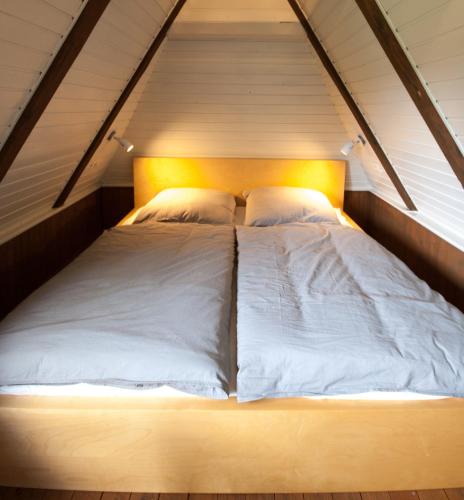 a bed with white sheets and pillows in a attic at Blockhaus Quellental in Odderade