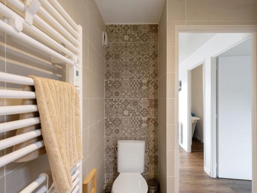 a bathroom with a toilet and a tile wall at Residence les Isards in Formiguères