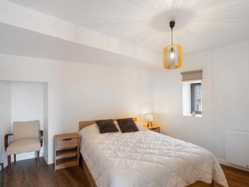 a white bedroom with a bed and a chair at Residence les Isards in Formiguères