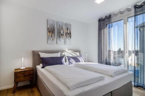 a white bedroom with a large bed and a window at Purer Genuss - Exklusive in Owingen