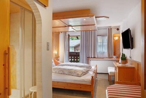 a bedroom with a bed and a window and a television at Ferienwohnung Piburgersee in Oetz