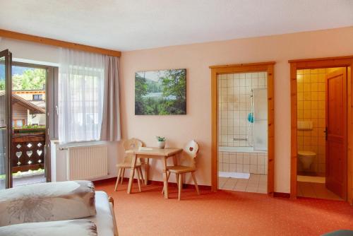 a room with a bed and a table and a bathroom at Ferienwohnung Piburgersee in Oetz