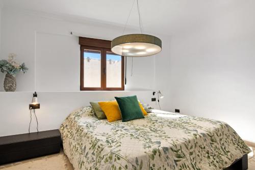 a bedroom with a bed with yellow and green pillows at Somni in Jávea