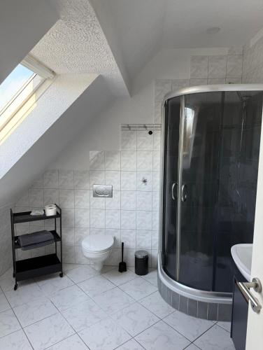 a white bathroom with a shower and a toilet at Ferienwohnung Waldblick Alterkülz in Alterkülz