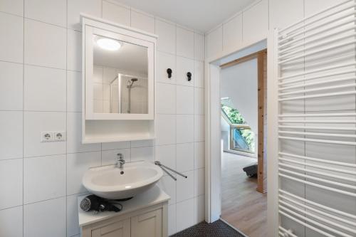 a white bathroom with a sink and a mirror at Ferienwohnung am Hirschfelsen in Bühlertal