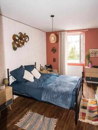 a bedroom with a blue bed and a window at Les dames du pont in Pontgibaud