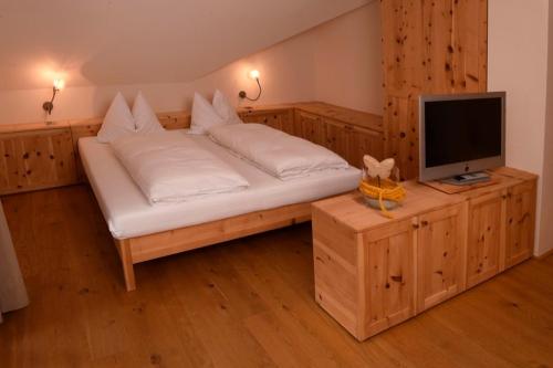 a bedroom with a bed and a tv on a wooden cabinet at Rosengartnerhof Apt Vorberg in Terlano