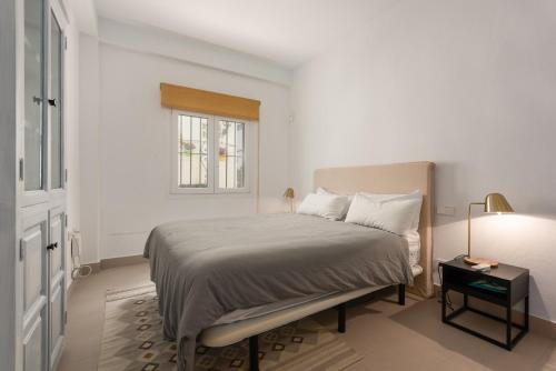a white bedroom with a bed and a window at Vivienda Casares in Estepona