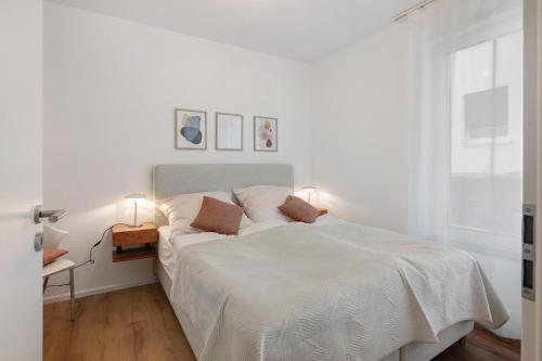 a white bedroom with a bed and a window at Ferienwohnung Panoramablick in Lörrach