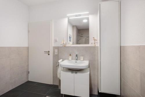 a white bathroom with a sink and a mirror at Ferienwohnung Panoramablick in Lörrach