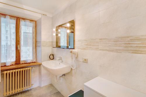 a white bathroom with a sink and a mirror at A Due Passi Valdidentro in Valdidentro