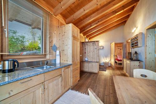 a kitchen with wooden cabinets and a wooden floor at Grushof App Paföl in Sluderno
